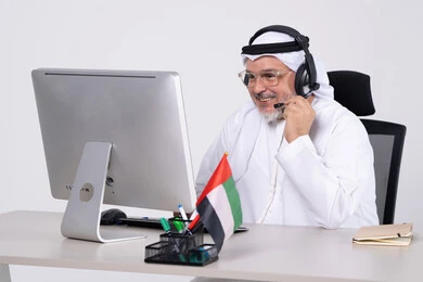 Emirati Businessman Wearing Headset at Office Desk