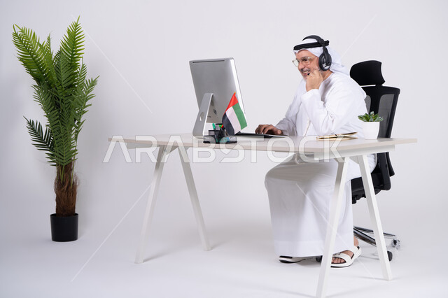 رجل إماراتي يعمل على الكمبيوتر في مكتب أبيض