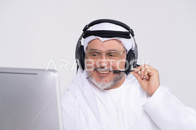 رجل إماراتي يرتدي سماعة رأس يعمل في المكتب