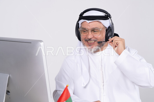 رجل إماراتي يرتدي سماعة رأس ويعمل على الكمبيوتر