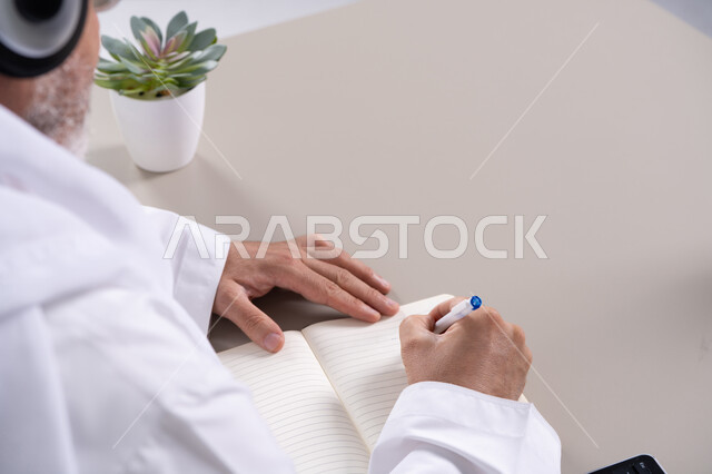 رجل إماراتي يكتب في دفتر ملاحظات على المكتب