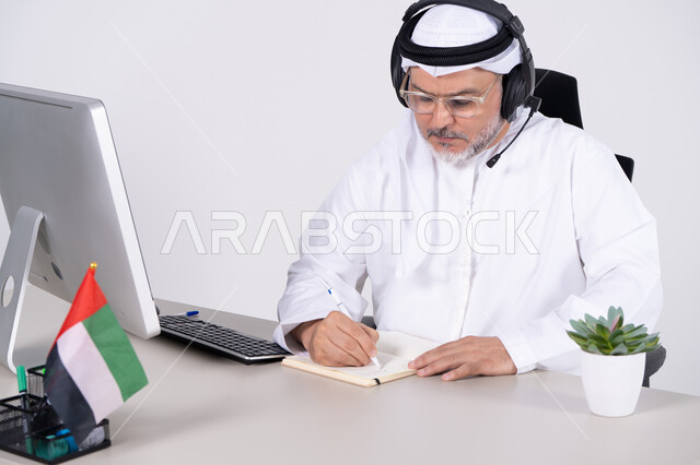 رجل أعمال إماراتي يعمل على مكتبه مع علم الإمارات