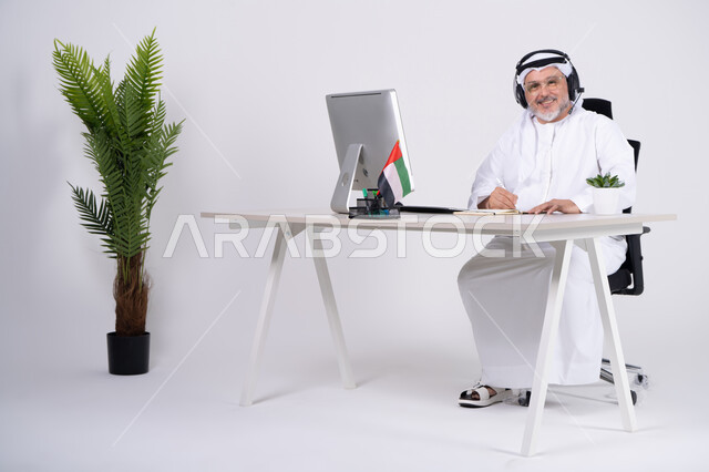 رجل أعمال إماراتي جالس في مكتبه مع سماعة رأس