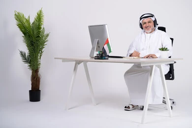 رجل أعمال إماراتي جالس في مكتبه مع سماعة رأس