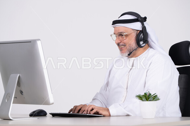 رجل أعمال إماراتي يعمل على الحاسوب بسماعة رأس