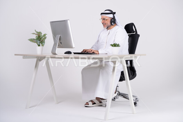 رجل إماراتي يعمل على الكمبيوتر باللباس التقليدي