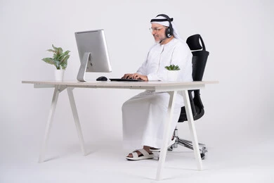 رجل إماراتي يعمل على الكمبيوتر باللباس التقليدي