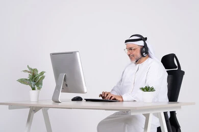رجل إماراتي يعمل على الكمبيوتر مع سماعة رأس