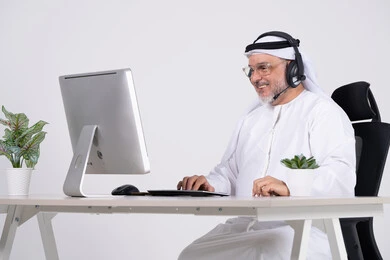 Emirati Businessman with Headset at Computer Desk