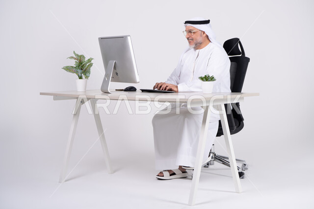 رجل أعمال إماراتي يعمل على كمبيوتر مكتبي