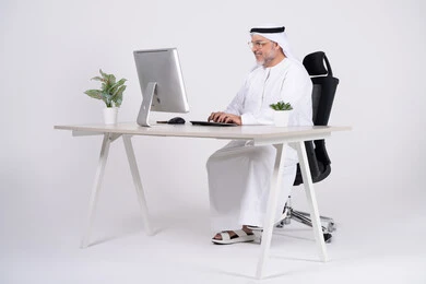 رجل أعمال إماراتي يعمل على كمبيوتر مكتبي