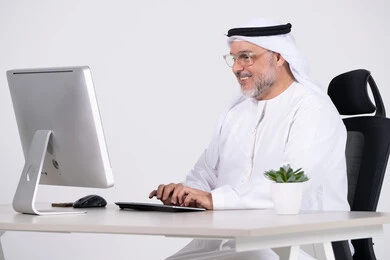 رجل أعمال إماراتي يعمل على الكمبيوتر في المكتب