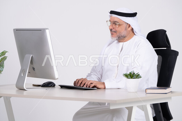 رجل أعمال إماراتي يعمل على كمبيوتر مكتبي في المكتب