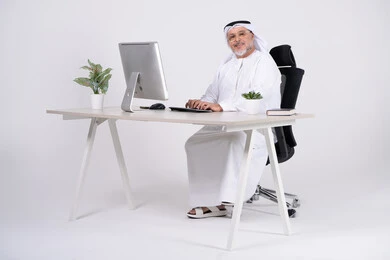 رجل أعمال إماراتي على مكتب عمل حديث مع كمبيوتر