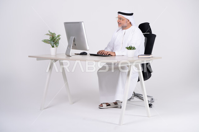 رجل أعمال إماراتي يعمل على الكمبيوتر في المكتب