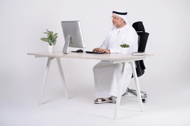 رجل أعمال إماراتي يعمل على الكمبيوتر في المكتب