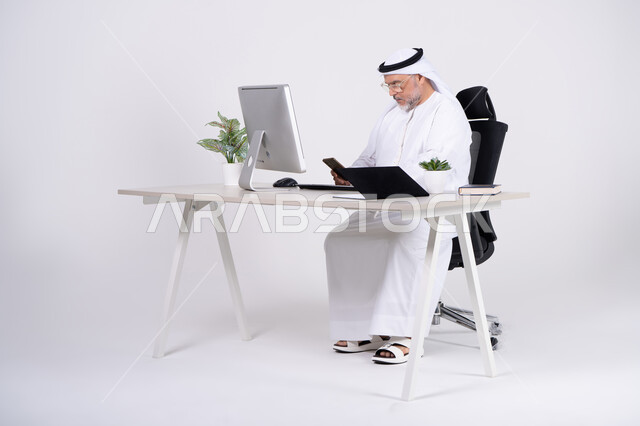 رجل أعمال إماراتي في المكتب يستخدم الهاتف الذكي