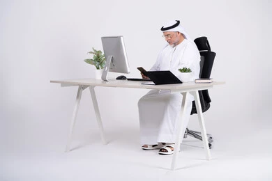 رجل أعمال إماراتي في المكتب يستخدم الهاتف الذكي