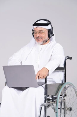 Emirati Man in Wheelchair Using Laptop with Headset