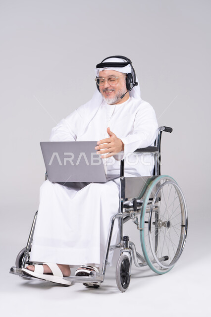 Emirati Man in Wheelchair Using Laptop with Headset