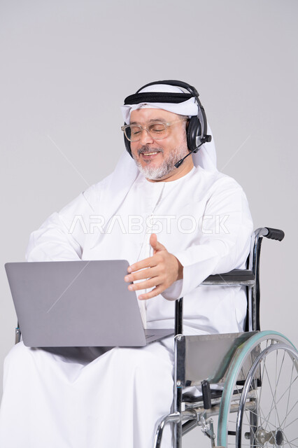 رجل إماراتي على كرسي متحرك يستخدم اللابتوب
