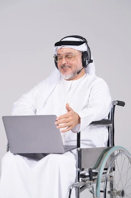 رجل إماراتي على كرسي متحرك يستخدم اللابتوب