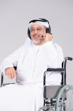 رجل إماراتي على كرسي متحرك يرتدي سماعة