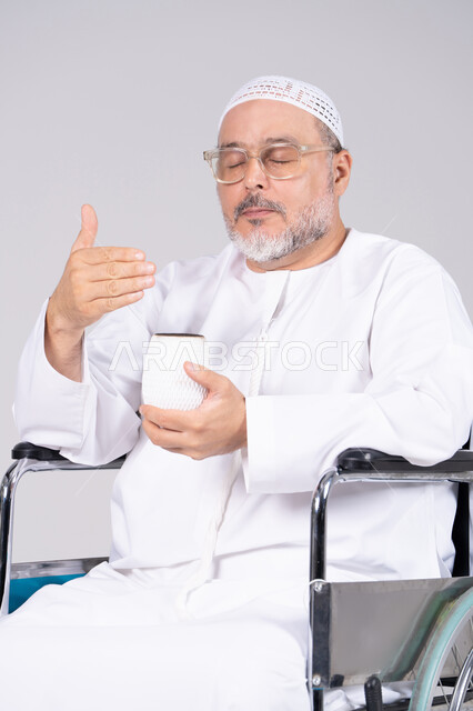 Elderly Emirati Man in Wheelchair with Cup