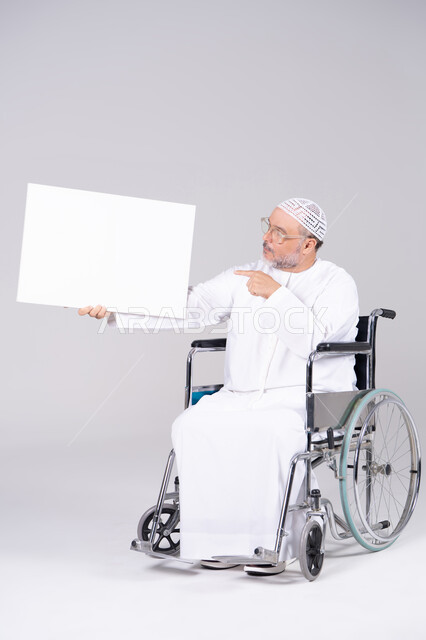رجل إماراتي على كرسي متحرك يحمل لوحة بيضاء