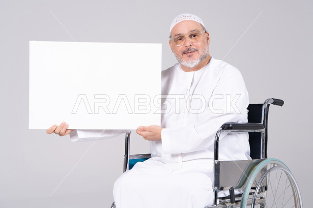 رجل إماراتي مسن على كرسي متحرك يحمل لوحة بيضاء