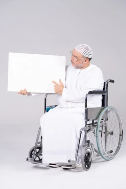رجل إماراتي مسن على كرسي متحرك يحمل لوحة فارغة