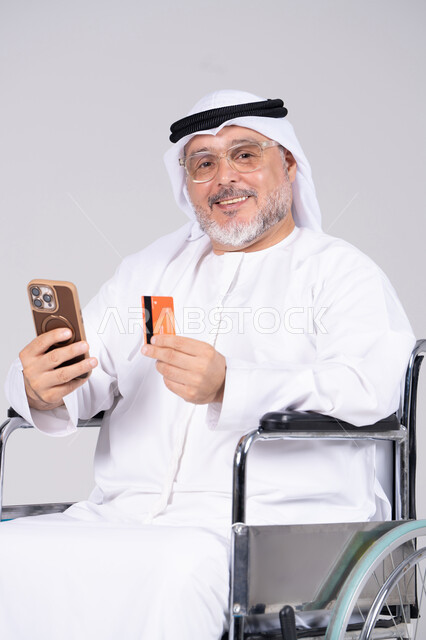رجل إماراتي مسن على كرسي متحرك يحمل بطاقة ائتمان