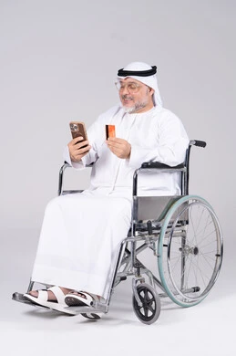 Emirati Man in Wheelchair Using Phone and Credit Card