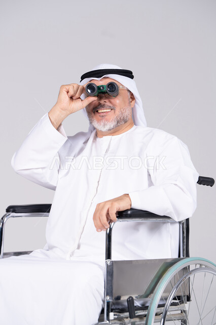 رجل إماراتي مسن على كرسي متحرك يستخدم المنظار