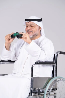 رجل إماراتي مسن على كرسي متحرك يمسك بالمنظار