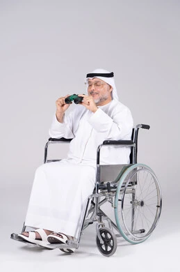 رجل إماراتي مسن على كرسي متحرك يحمل منظار