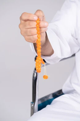 رجل إماراتي يمسك بمسبحة برتقالية لقطة مقربة