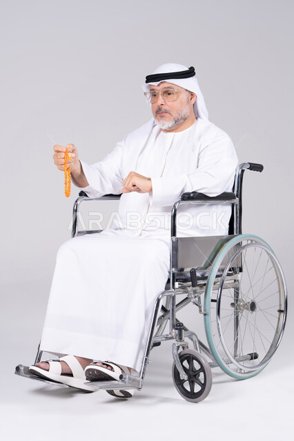 رجل إماراتي مسن على كرسي متحرك بخلفية بيضاء