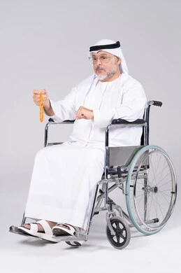 رجل إماراتي مسن على كرسي متحرك بخلفية بيضاء
