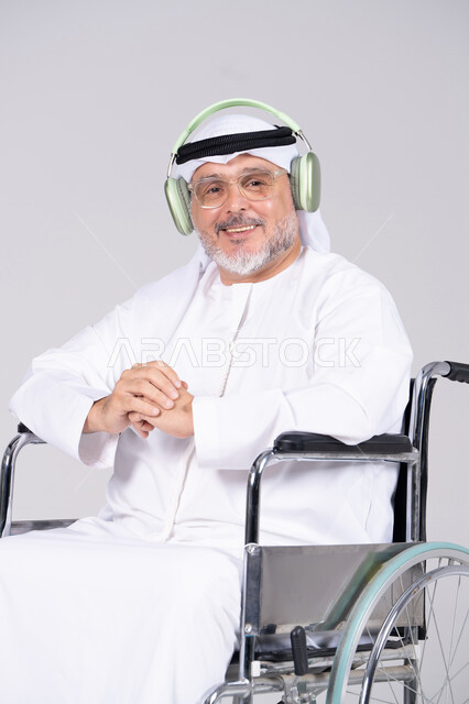 رجل إماراتي مسن على كرسي متحرك مع سماعات