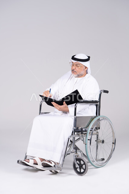 رجل إماراتي مسن على كرسي متحرك يكتب في الاستوديو