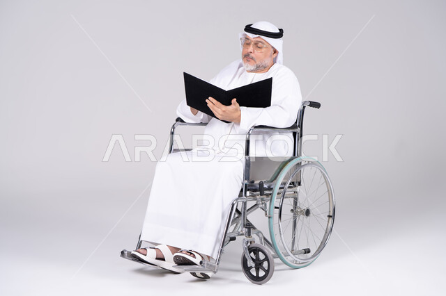 رجل إماراتي مسن على كرسي متحرك يحمل ملفاً