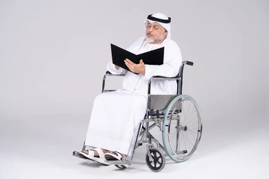 رجل إماراتي مسن على كرسي متحرك يحمل ملفاً