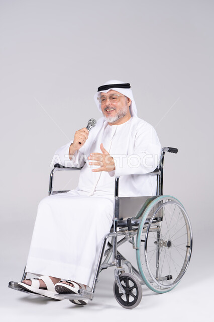 رجل إماراتي على كرسي متحرك يمسك ميكروفون