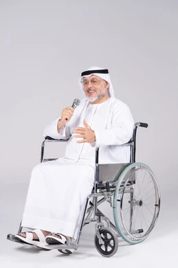 رجل إماراتي على كرسي متحرك يمسك ميكروفون