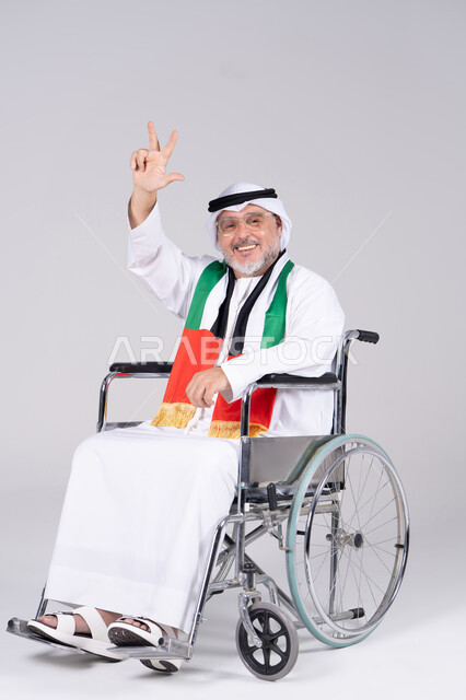 رجل إماراتي مسن على كرسي متحرك بعلم الإمارات