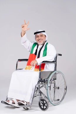 رجل إماراتي مسن على كرسي متحرك بعلم الإمارات