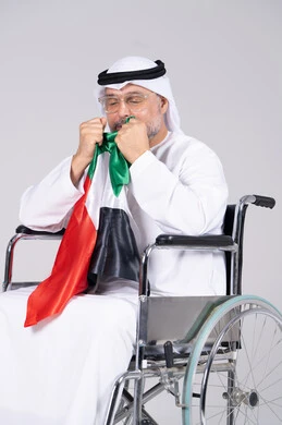 رجل إماراتي على كرسي متحرك يحمل علم الإمارات