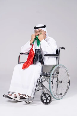رجل إماراتي على كرسي متحرك يحمل علم الإمارات