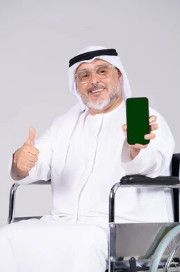 رجل إماراتي على كرسي متحرك يحمل هاتف شاشة خضراء